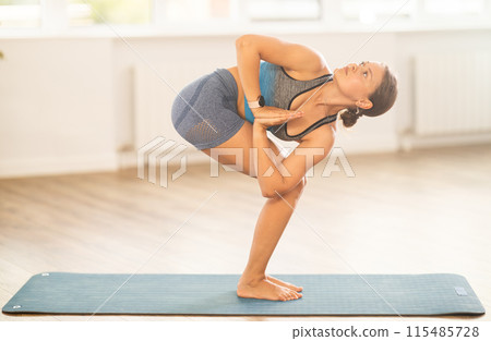 Lover of active lifestyle on yoga mat perform doing Parivritta Uttanasana in gym Lover of active lifestyle on yoga mat perform doing Parivritta Uttanasana in gym 115485728