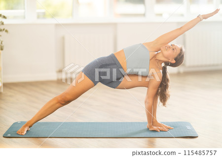 Young woman practicing yoga in parivritta virabhadrasana pose Young woman practicing yoga in parivritta virabhadrasana pose 115485757