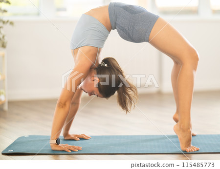 Young woman performing advanced Chakrasana yoga asana Young woman performing advanced Chakrasana yoga asana 115485773