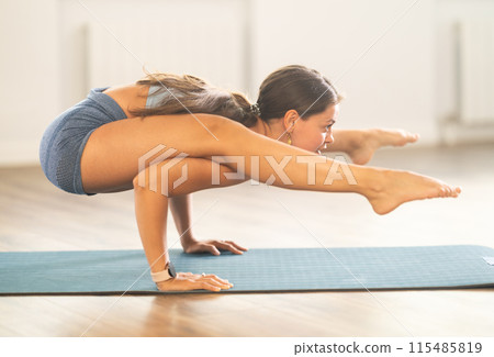 Lover of active lifestyle on yoga mat perform doing Bhujapidasana in gym 115485819