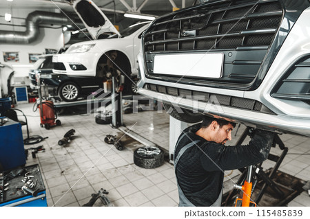 Auto mechanic repairs running gear of a car in car service Auto mechanic repairs running gear of a car in car service 115485839