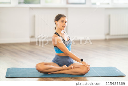 Young woman practicing parivritta sukhasana yoga pose 115485869