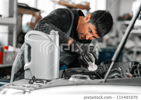 Close up of car service worker pouring new oil into car engine 115485870