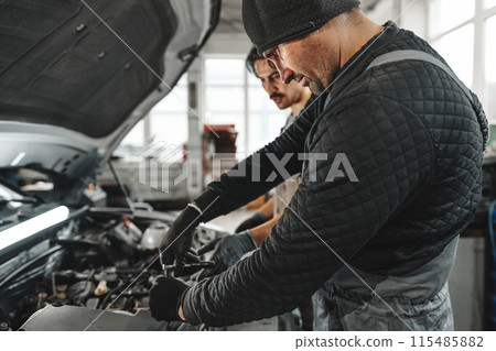 Two male mechanics repairing car in car service Two male mechanics repairing car in car service 115485882