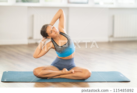 Fit young girl performing seated stretch in Lotus Pose 115485892