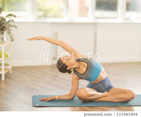 Lover of active lifestyle on yoga mat perform doing variations of padmasan in gym Lover of active lifestyle on yoga mat perform doing variations of padmasan in gym 115485944