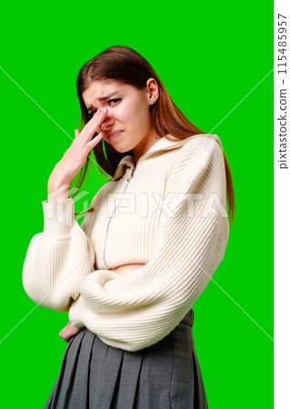 Woman Expressing Discomfort With Hand on Forehead Against Green Background 115485957