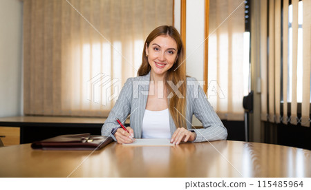 Female lawyer sitting at desk and smiling 115485964