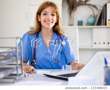 Woman doctor sitting at workplace with computer in her office Woman doctor sitting at workplace with computer in her office 115486015
