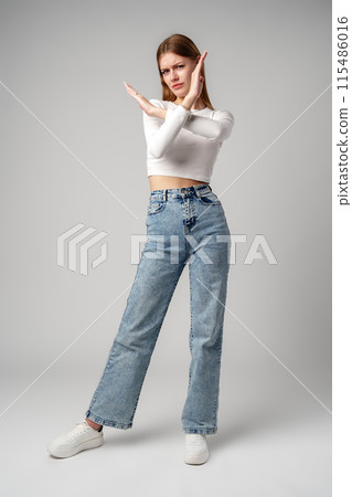 Young Woman Making Stop Gesture Against Grey Background. Young Woman Making Stop Gesture Against Grey Background. 115486016