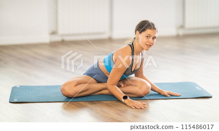 Young fit woman doing stretching exercise in Padmasana pose Young fit woman doing stretching exercise in Padmasana pose 115486017