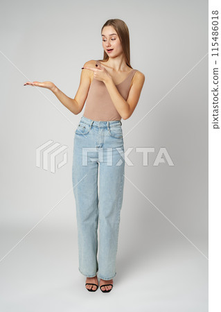 Young Woman in Tank Top Pointing at Something on gray background Young Woman in Tank Top Pointing at Something on gray background 115486018