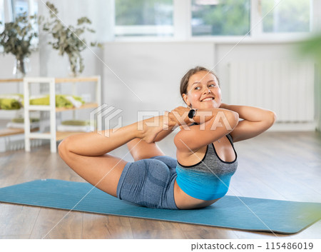 Lover of active lifestyle on yoga mat perform doing dhanurasana n gym Lover of active lifestyle on yoga mat perform doing dhanurasana n gym 115486019