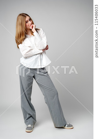 Joyful Young Blonde Woman Smiling against gray background 115486033