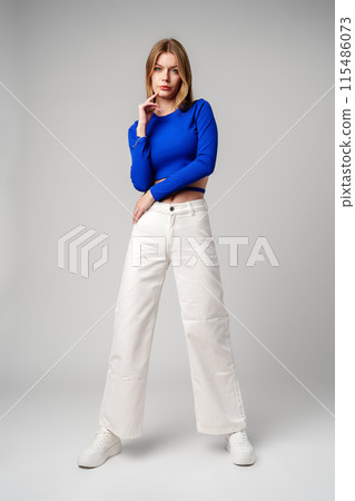 Young Woman model in Blue Top and White Pants posing on white background Young Woman model in Blue Top and White Pants posing on white background 115486073