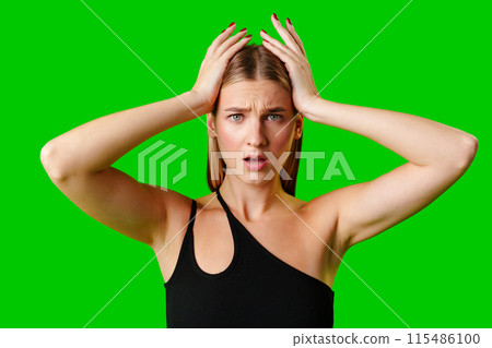 Young Woman Holding Hands Up to Head against green background Young Woman Holding Hands Up to Head against green background 115486100