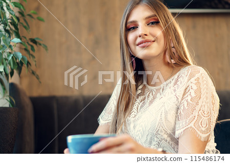Nice young woman enjoying cup of coffee in a coffee shop Nice young woman enjoying cup of coffee in a coffee shop 115486174