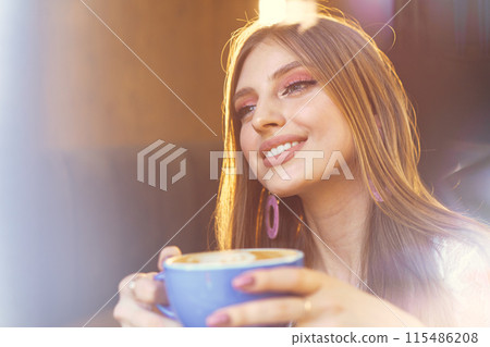Portrait of a young woman having a cup of coffee and looking through the window 115486208