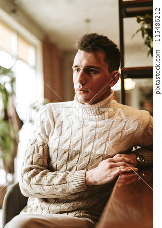 Man Sitting at a Table With Arms Crossed Man Sitting at a Table With Arms Crossed 115486212