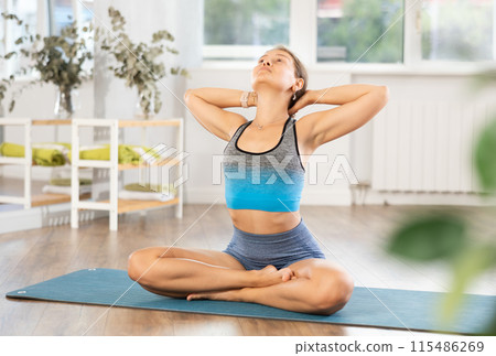 Sportive girl practicing lotus pose of yoga in light room 115486269