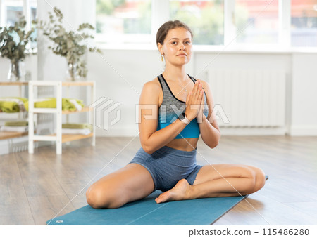 Lover of active lifestyle on yoga mat perform doing butterfly pose in gym Lover of active lifestyle on yoga mat perform doing butterfly pose in gym 115486280