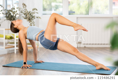 Young woman practicing yoga in setu bandhasana pose 115486291