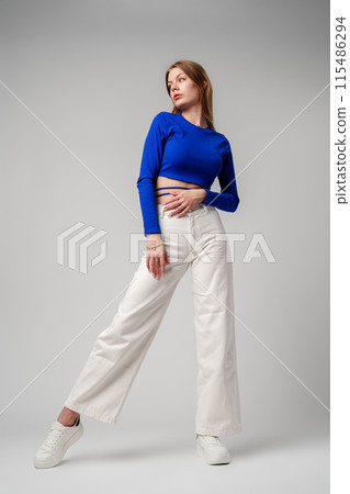 Young Woman model in Blue Top and White Pants posing on white background 115486294
