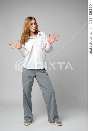 Joyful Young Blonde Woman Smiling against gray background Joyful Young Blonde Woman Smiling against gray background 115486350