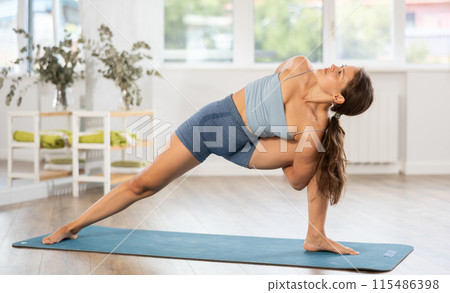 Young woman practicing yoga in parivritta virabhadrasana pose Young woman practicing yoga in parivritta virabhadrasana pose 115486398