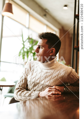 Man Sitting at a Table With Arms Crossed Man Sitting at a Table With Arms Crossed 115486410