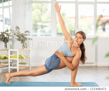 Lover of active lifestyle on yoga mat perform doing elongated side angle in gym 115486472