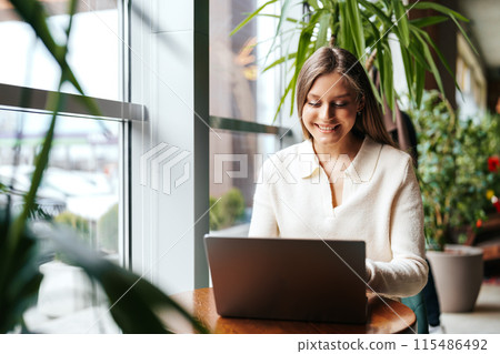 Woman Sitting at Table Using Laptop Computer 115486492