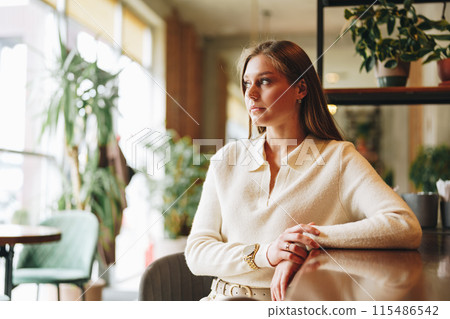 Woman Sitting at a Table in a Restaurant Woman Sitting at a Table in a Restaurant 115486542