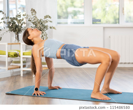 Sporty girl performing Reverse Table Top Pose in yoga studio 115486580