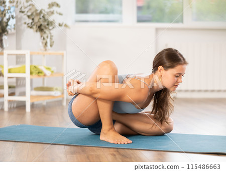 Sporty young woman practicing yoga in serene studio Sporty young woman practicing yoga in serene studio 115486663