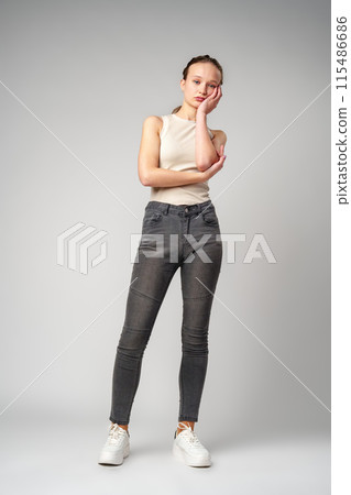 Young Woman Grimacing in Displeasure Against a Neutral Background 115486686