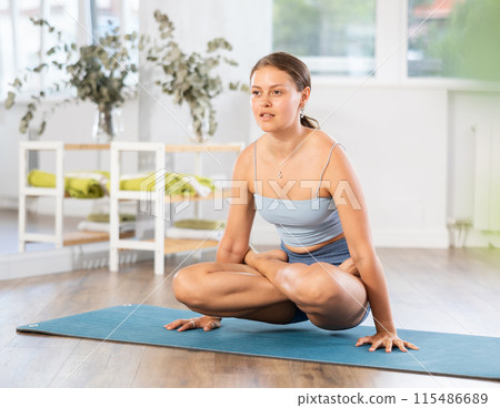 Young woman practicing yoga in kukkutasana pose Young woman practicing yoga in kukkutasana pose 115486689
