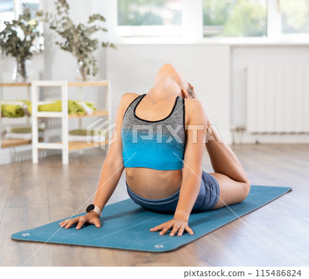 Sportive girl practicing cobra pose of yoga in light room 115486824
