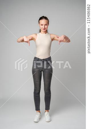 Young Woman in Tank Top Pointing Down in studio 115486862