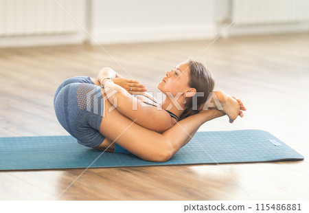 Lover of active lifestyle on yoga mat perform doing yoganidrasan in gym Lover of active lifestyle on yoga mat perform doing yoganidrasan in gym 115486881