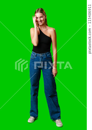 Smiling Young Woman in Casual Outfit Posing Against Green Background 115486911