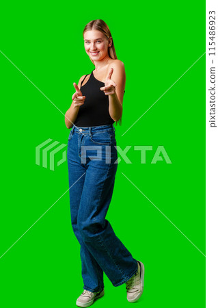 Young Woman Pointing at Something against green background 115486923