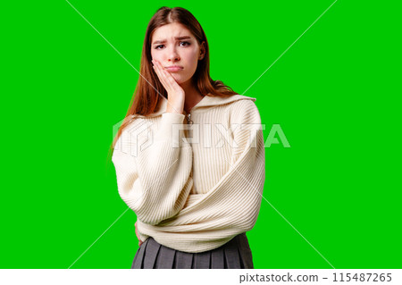Young Woman Looking Bored and Disinterested Against Green Background Young Woman Looking Bored and Disinterested Against Green Background 115487265