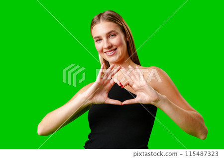 Young Woman Making Heart With Hands on green background Young Woman Making Heart With Hands on green background 115487323