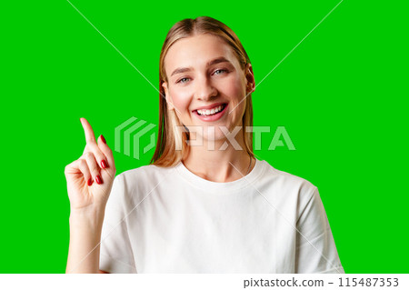 Young Woman Pointing Up Against Green Background Young Woman Pointing Up Against Green Background 115487353