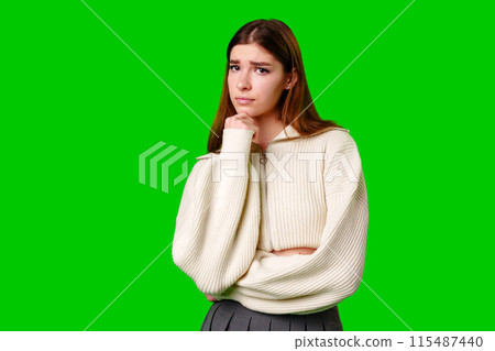 Young Woman Deep in Thought Against a Green Screen Background 115487440
