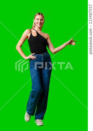 Young Woman Pointing at Something against green background Young Woman Pointing at Something against green background 115487557