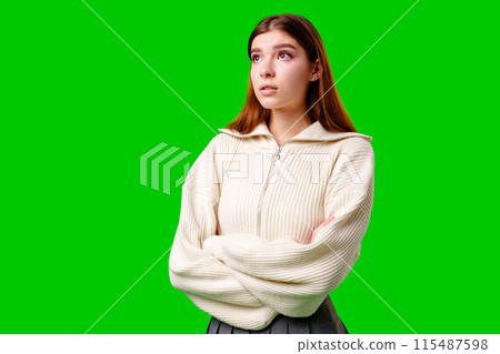 Young Woman With Crossed Arms Looking Thoughtfully to the Side Against Green Background Young Woman With Crossed Arms Looking Thoughtfully to the Side Against Green Background 115487598