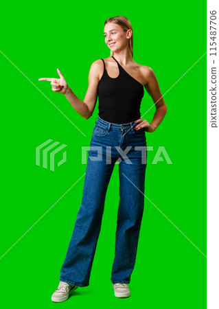 Young Woman Pointing at Something against green background 115487706