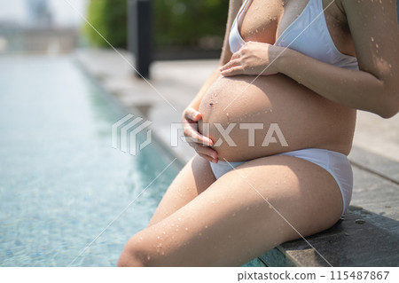 A portrait of happy Asian pregnant woman by the swimming pool. People lifestyle in travel holiday vacation concept. Relaxation. Having a baby. Family people lifestyle. Mom love. A portrait of happy Asian pregnant woman by the swimming pool. People lifestyle in travel holiday vacation concept. Relaxation. Having a baby. Family people lifestyle. Mom love. 115487867